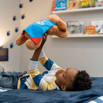 Young boy laying on his bed holding up a Snuggle Puppy Hero in the air